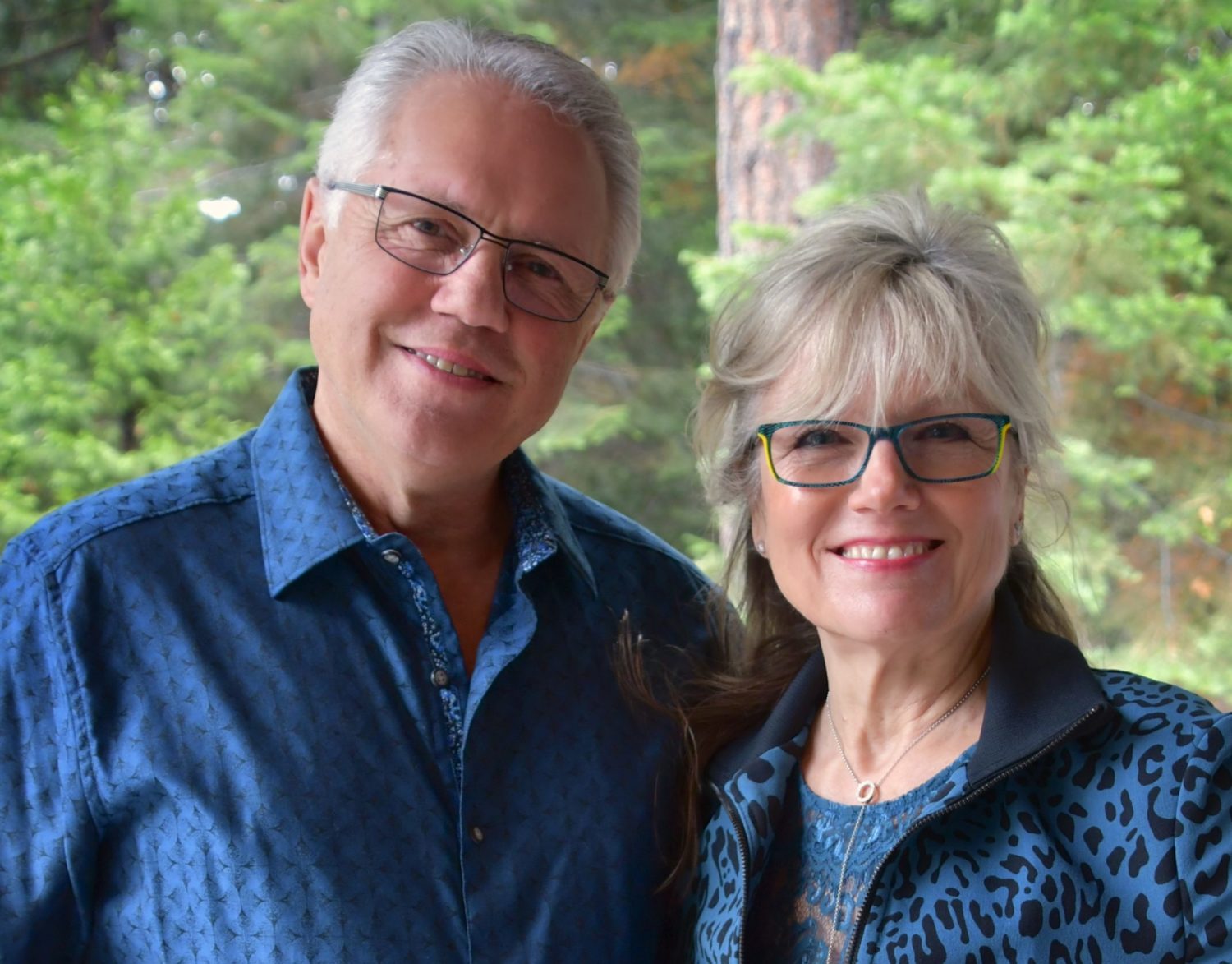 headshots of Bill and Joann Truby standing in blue shirts in front of tree backdrop - Truby Achievements a leading source for leadership and management training