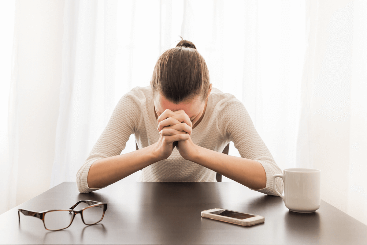 woman with head in her hands at a desk - quick stress test on truby achievements website