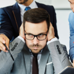 businessman covering his ears with yelling team members - featured image for dealing with team problems blog by truby achievements