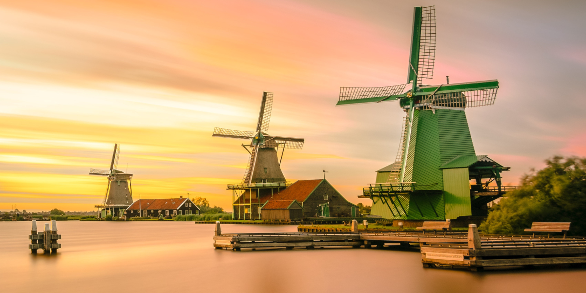 windmills along a water edge with a sunset in the back - featured image for dealing with difficulties blog by truby achievements